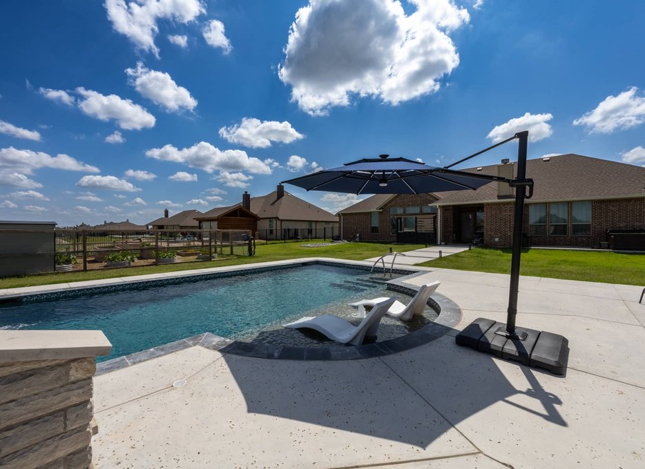 Backyard pool with tanning shelf and cantilever umbrella