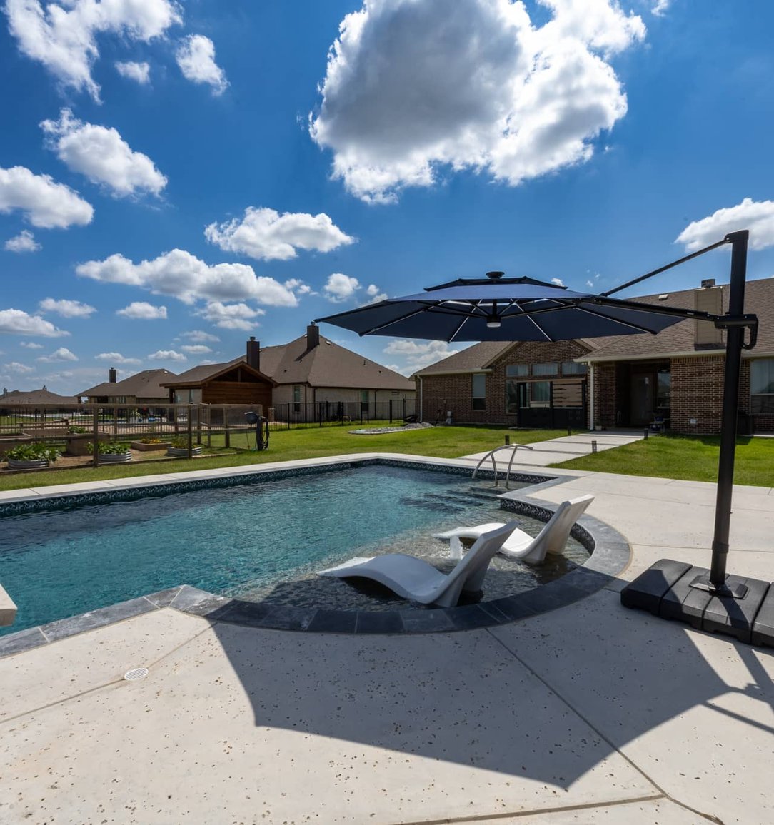Backyard pool with tanning shelf and cantilever umbrella