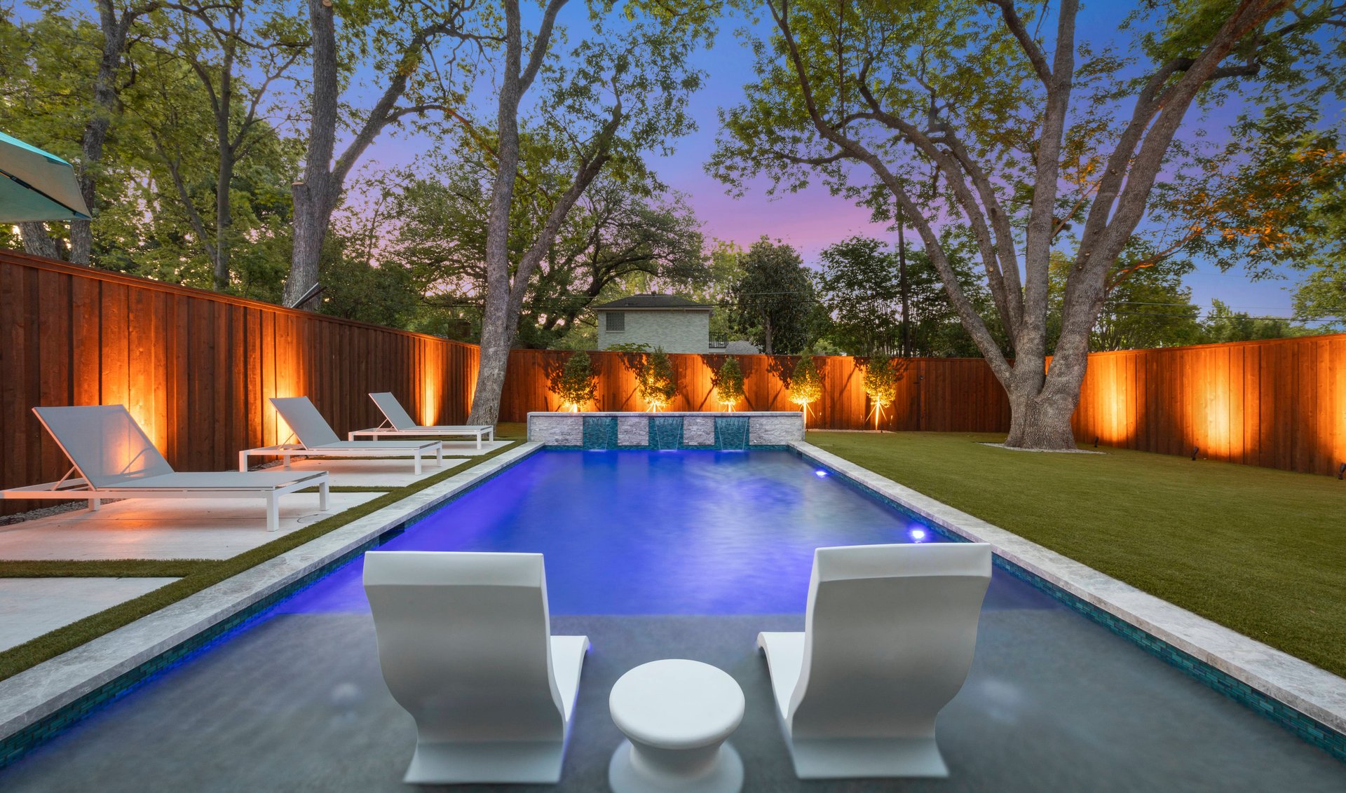Illuminated pool with water feature at dusk