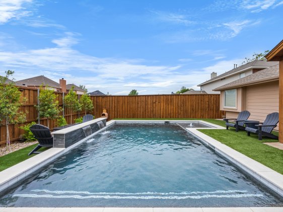 Rectangular pool with waterfall feature and turf surround