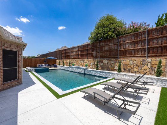 Lap pool with stone wall and lounge chairs