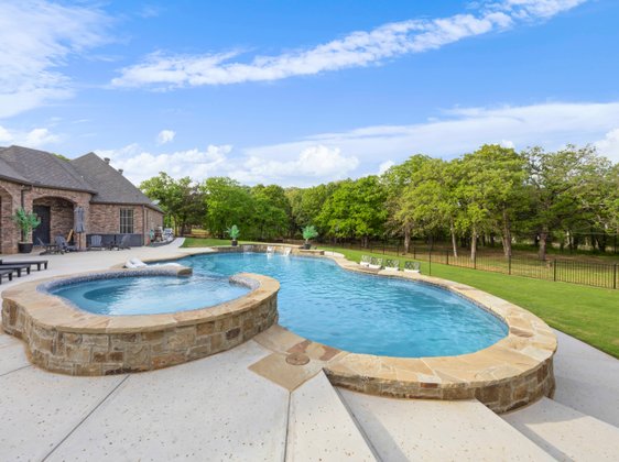 Freeform pool with elevated stone spa and waterfall